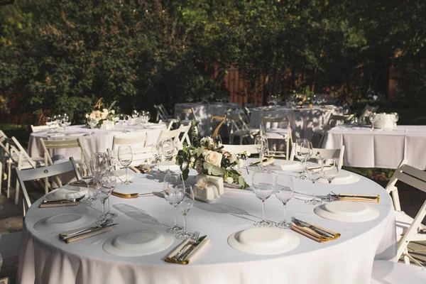 Свадебный стол украшен свежими цветами в медной вазе. Свадебная флористика. Банкетный стол для гостей на открытом воздухе с видом на зеленую природу. Аромат с розами, эустомой и листьями эвкалипта — стоковое фото