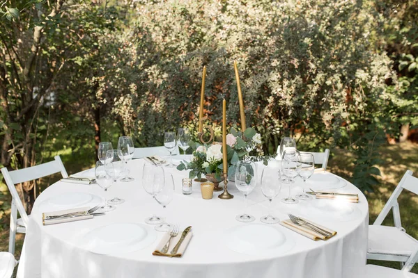 Mesa de boda decorada con flores frescas en un jarrón de latón. Floristería de bodas. Mesa de banquete para invitados al aire libre con vistas a la naturaleza verde. Ramo con rosas, eustoma y hojas de eucalipto — Foto de Stock