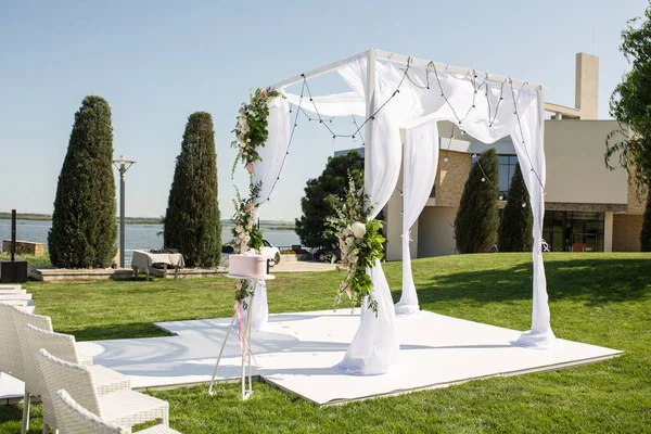 Beautiful outgoing wedding set up. Jewish Hupa  on romantic wedding ceremony , wedding outdoor on the lawn water view. Wedding decor. White wooden chairs on a green lawn. White armchairs for guests — Stock Photo, Image