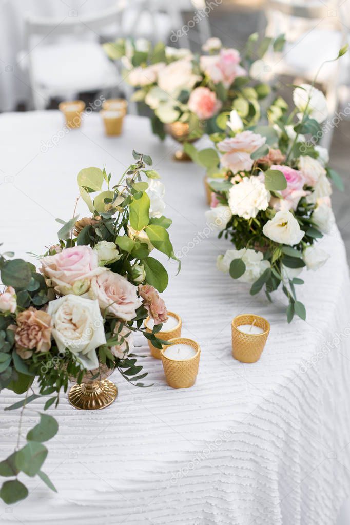 Wedding table setting decorated with fresh flowers in a brass va