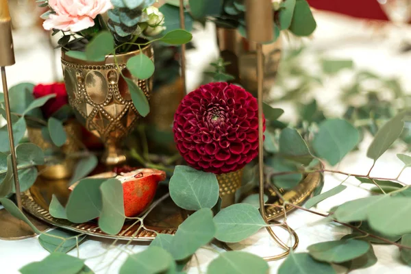 Feestelijk versierde bankettafel in het restaurant. Verse bloemen zijn gouden kaarsen en rode stoelen en granaat. duur rijk — Stockfoto