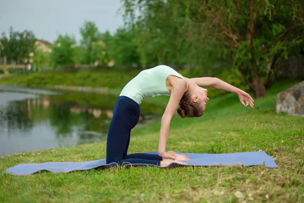 Delgado joven morena yogui realiza ejercicio de yoga complejo en gr — Foto de Stock