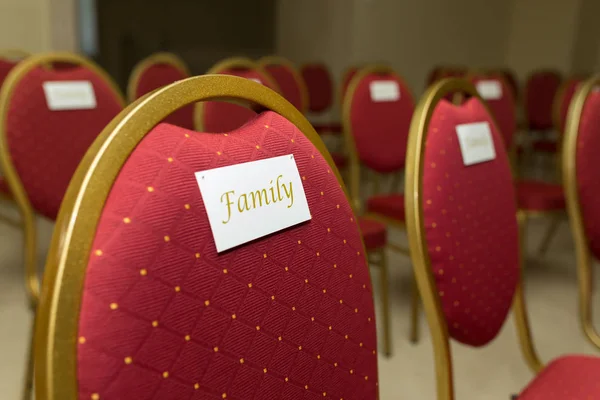 Wedding ceremony in the banquet hall indoors. Rows of chairs for guests at the wedding. A chair in red velvet with gold and a nameplate family — Stock Photo, Image