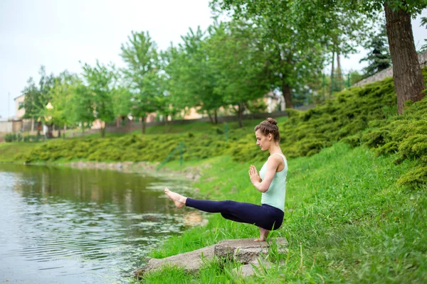Тонка брюнетка дівчина робить йогу влітку на зеленому газоні — стокове фото