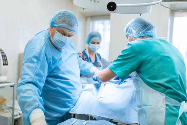 Um cirurgião experiente em uma máscara e vestido opera em um estéril — Fotografia de Stock