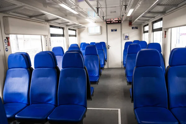 The interior of the transfer train to the airport. Rows of blue armchairs. Without people.