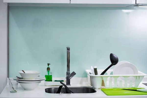 A mountain of dirty dishes in the kitchen sink. Mess in the house.