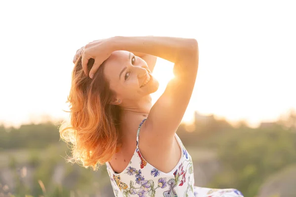 丘のある野原で夕日を楽しむ優しい赤い髪の女の子 — ストック写真