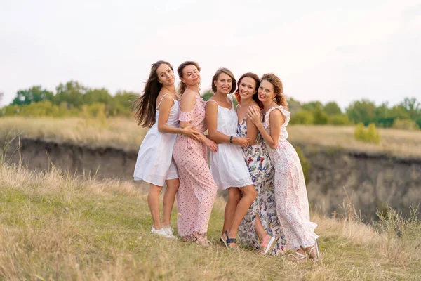 A cheerful company of beautiful girls friends enjoy the company and have fun together in a picturesque place of green hills