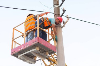 Sütunlardaki elektrikçiler elektrik hattına monte ediyorlar. Profesyonel elektrikçiler kulede çalışıyor. Dnipro / Ukrayna - 08.10.2019