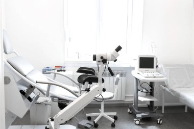 The interior of the gynecologists office. Gynecological chair, colposcope and ultrasound machine. clipart