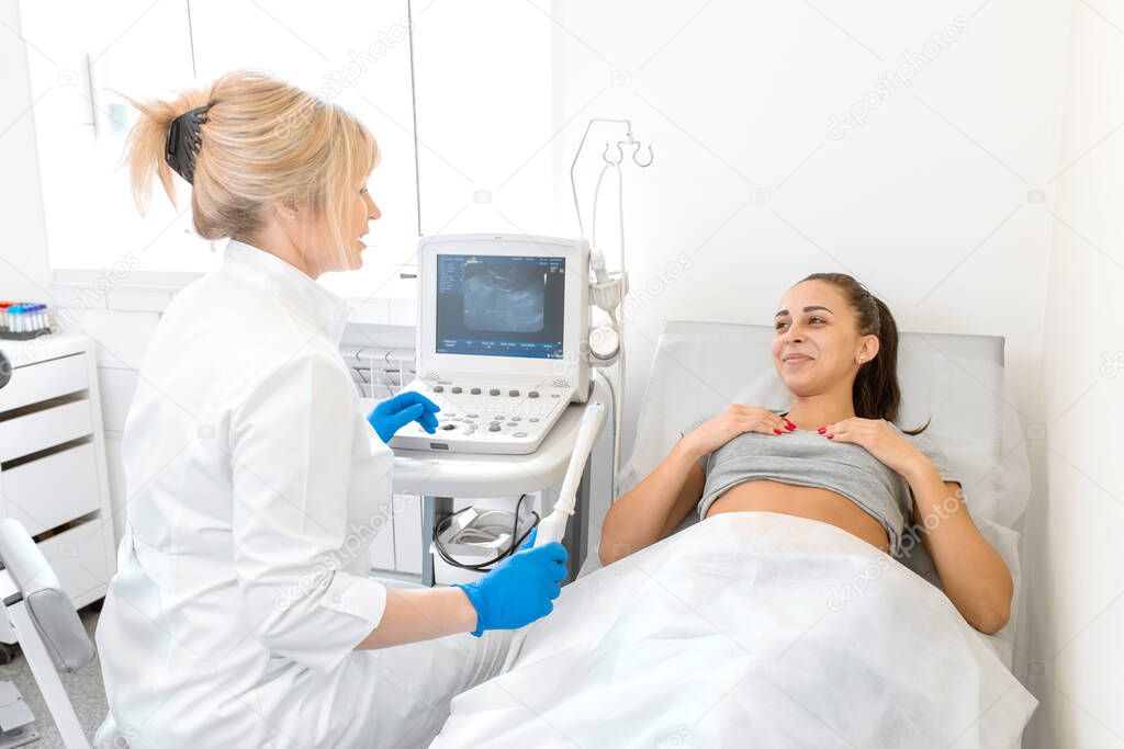 A gynecologist sets up an ultrasound machine to diagnose a patient who is lying on a couch. A transvaginal ultrasound scanner of the internal organs of the pelvis. Female health concept.