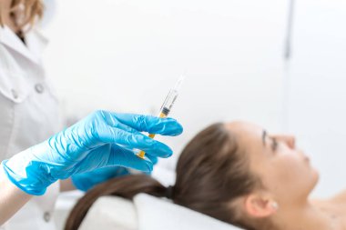 Güzellik uzmanı saçı güçlendirmek için kafa derisine vitamin iğnesi yapıyor.