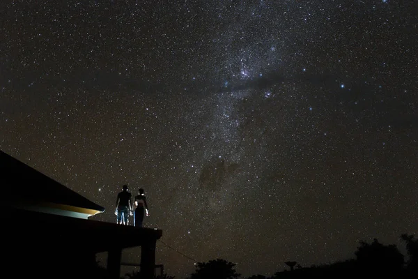 Couple on rooftop watching mliky way and stars in the night sky on Bali island