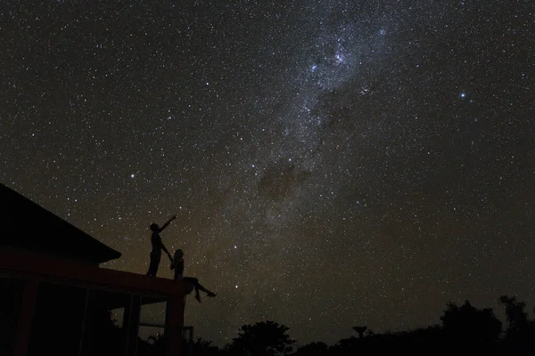 Couple on rooftop watching mliky way and stars in the night sky on Bali island