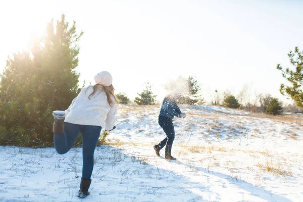 Loving couple play snowballs in winter in the forest. Throw each other snow. Laugh and have a good time.