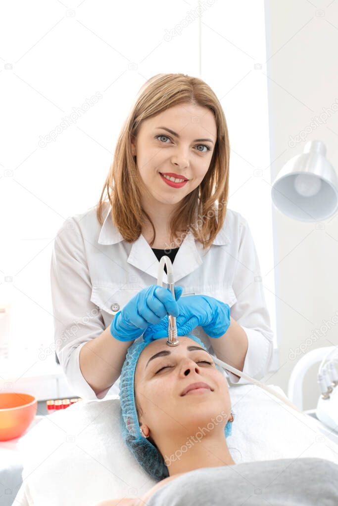 Beautician makes a young beautiful girl a facial vacuum treatment procedure. Facial care and rejuvenation. Increase epidermal tone.