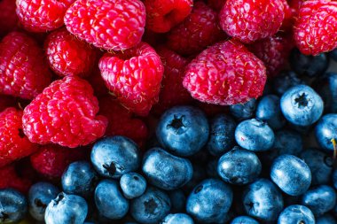 Ahududu ve siyah yaban mersininin yakın çekimi çerçeveyi ikiye böldü. Yaz vitaminleri.