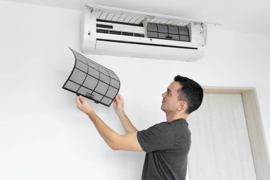 Adam evdeki klimanın filtresini tozdan temizliyor. Çok kirli bir klima filtresi. İklim ekipmanı bakımı