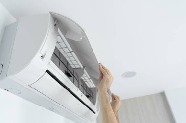 Adam evdeki klimanın filtresini tozdan temizliyor. Çok kirli bir klima filtresi. İklim ekipmanı bakımı