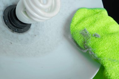 Evi temizliyorum. Lambadan çıkan yeşil bir bezle tozu sil. Enerji tasarrufu ampulü. Bir sürü toz.