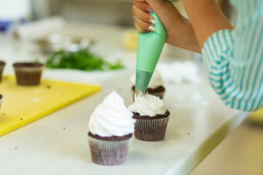 Çikolatalı kekleri havadar protein kremiyle süsleme süreci. Profesyonel pasta şefleri tarafından pastaların oluşturulması.