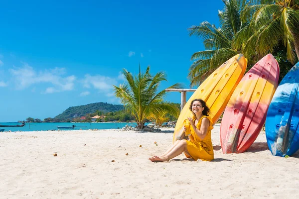 Dziewczyna Żółtej Sukience Tropikalnej Piaszczystej Plaży Pracuje Laptopie Pobliżu Kajaków — Zdjęcie stockowe