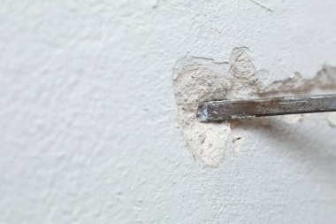 Binanın tamiri. Bir adam duvara kablo döşemek için hendek kazar. Duvara elektrik kabloları döşeniyor.