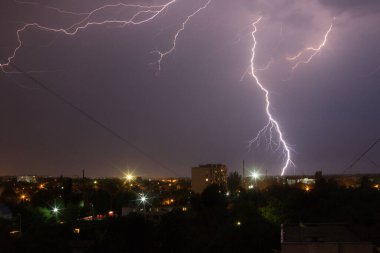 Mor ışıkta şehrin üzerinde şimşek fırtınası.