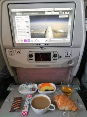 Uçakta yemek takımı ve başlığında uçağın uçuşunu gösteren bir ekran olan bir koltuk. Rahat uçuşlar. Dubai / BAE - 02.04.2018