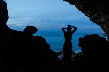 Kadın, okyanus sahilindeki balerin mağarasında gün batımını bekliyor..