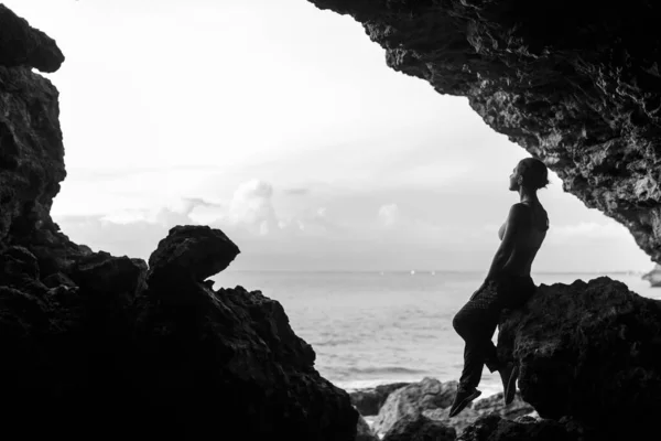 Woman wait sunset in balinesse cave at ocean beach.