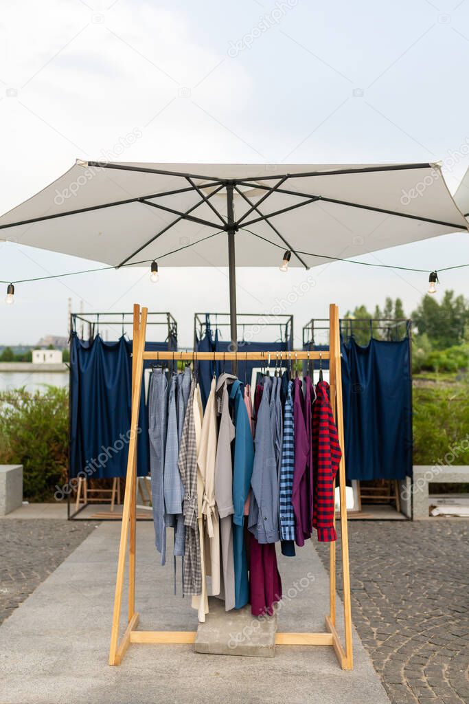 Racks with clothes outdoors. Designer sells clothes at a city fair.