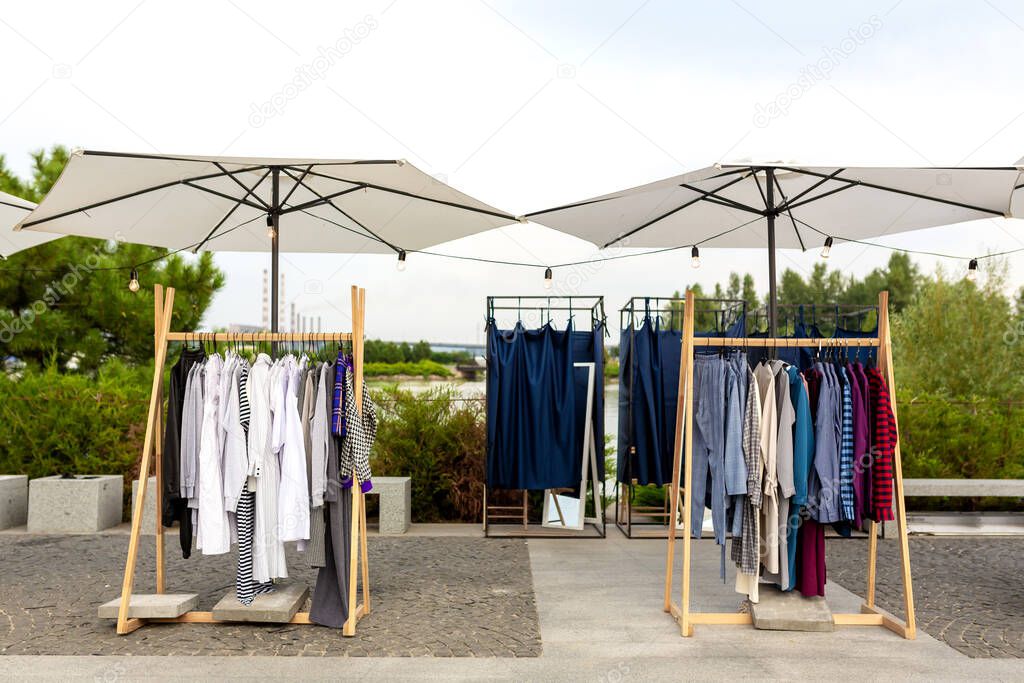 Racks with clothes outdoors. Designer sells clothes at a city fair.