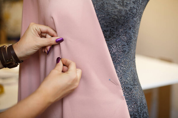 female dressmaker attach fabric to mannequin with needles. creating dress design. Tailor industry concept.