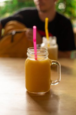 Plastik bardakta taze mango suyu ve frangipani çiçeği. Tropik içecekler.