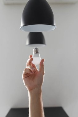 Lambanın ampulünü siyah lambayla değiştiriyorum. Açık gri arkaplanda.