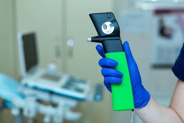 Professional equipment ophthalmologist tonometer. Doctor vet holds in his hand with a glove veterinary tonometer. Blurred background.