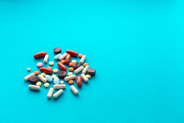 Mavi arka planda bir avuç renkli hap. Tıbbi konsept.