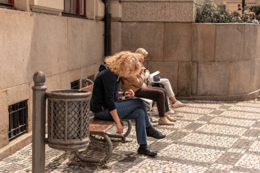 Kıvırcık saçlı adam bankta dinleniyor. Prag / Çek Cumhuriyeti - 05.21.2019