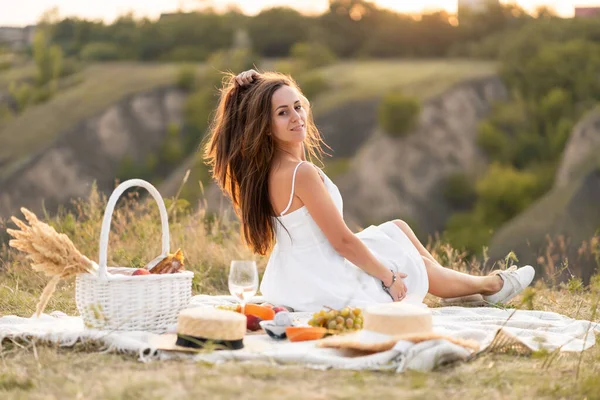 美しい場所でピクニックをしている白いサンドレスの豪華な若いブルネットの女の子 ロマンチックなピクニック — ストック写真
