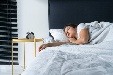 Kız çalar saatin yanında uyuyor. Kalkma vakti. Sabah 7 'de. Derin uyku.