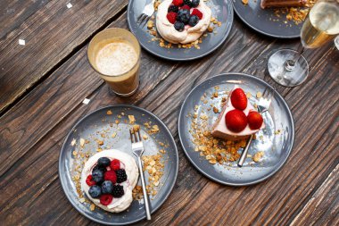 Üst manzara, ahşap bir masanın üzerinde yaz meyveleri olan tatlı kekler. Parti, güzel masa. Lokantada yaz tatlısı.