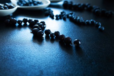 Siyah bir masada beyaz bir tabakta farklı türde siyah böğürtlen. Şık mevsimlik vitaminler.