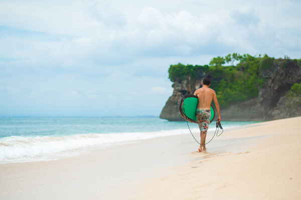 Surfer. Surfing Man With Surfboard Walking On Sandy tropical Beach. Healthy Lifestyle, water activities, Water Sport. Beautiful Ocean