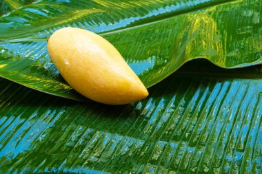 Islak muz yaprağında olgun sarı mango meyvesi. Doğal yiyecek..