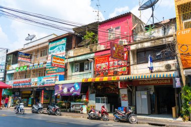 Asya şehrinin her zamanki caddesi. Çok renkli alçak binalar ve motosikletler. Bangkok / Tailand - 02.04.2020