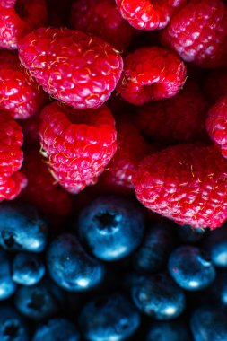 Ahududu ve siyah yaban mersininin yakın çekimi çerçeveyi ikiye böldü. Yaz vitaminleri.