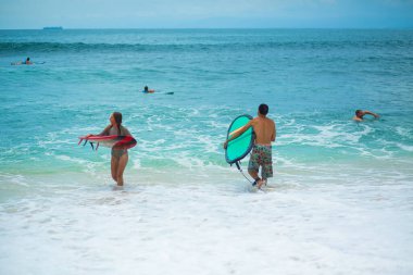 Sörfçü. Sörf tahtası olan sörfçü adam kumsalda yürüyor. Sağlıklı yaşam tarzı, su aktiviteleri, Su Sporu. Güzel Okyanus. Bali, Endonezya - 03 / 24 / 2018