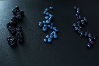 Siyah bir masada farklı türde böğürtlenlerin karışımı. Şık mevsimlik vitaminler.